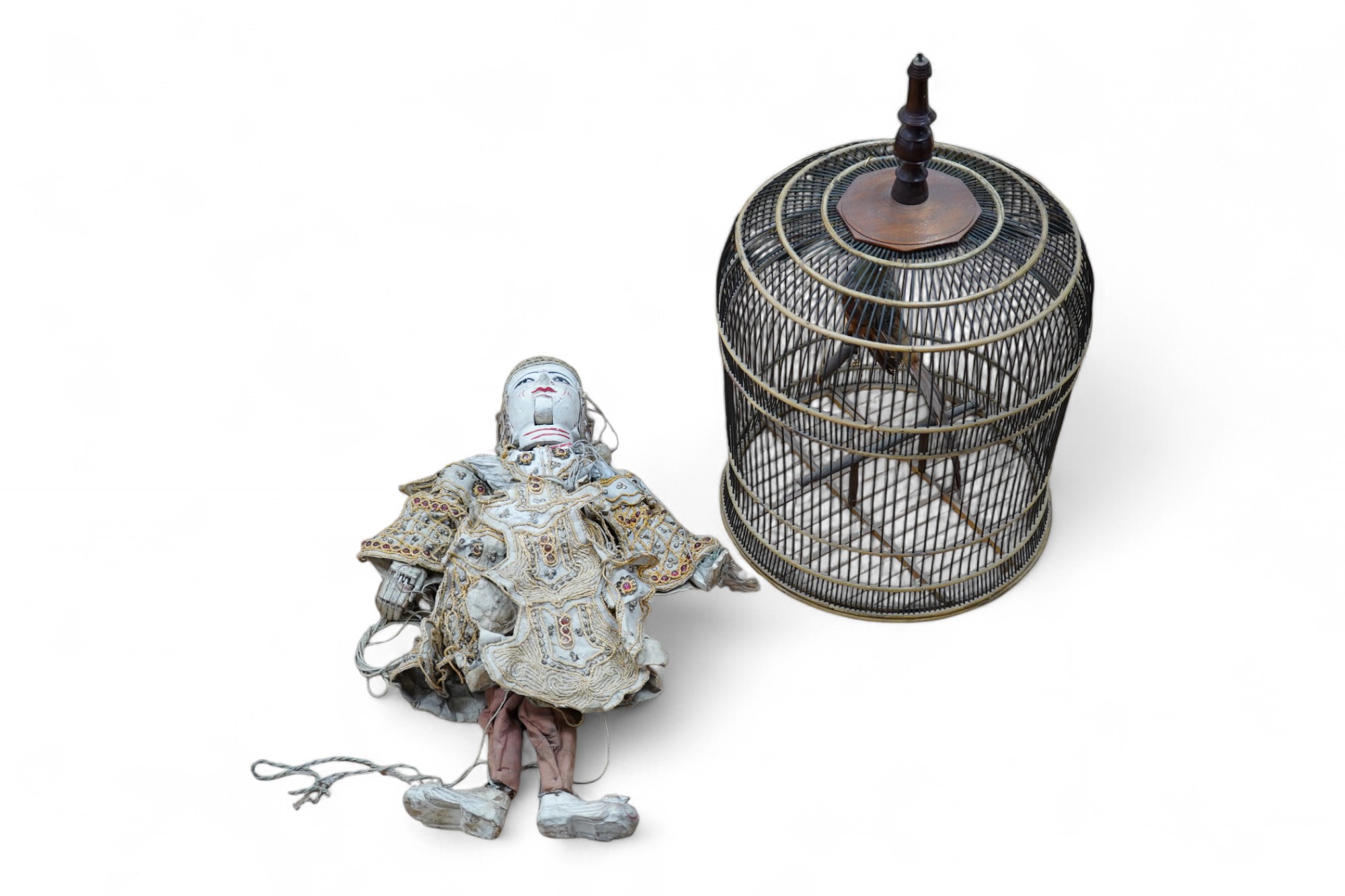 A Thai painted wood puppet, with sequined fabric costume and a wire and rattan circular bird cage, 65cm. Condition - fair